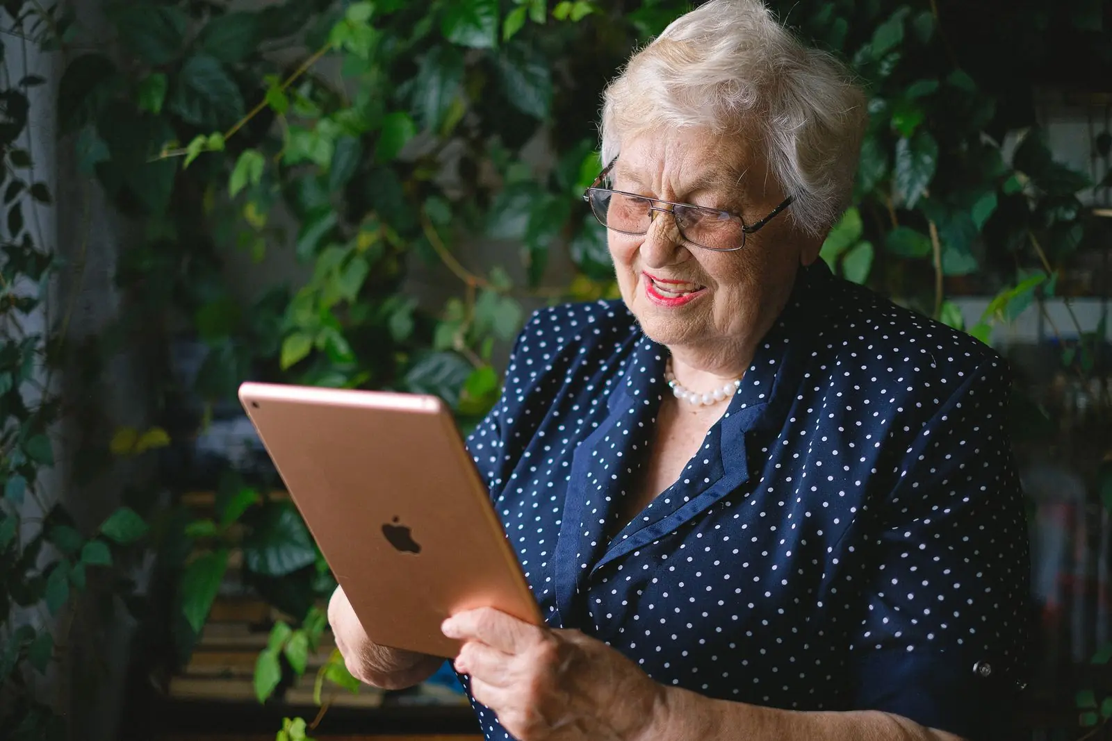 An older woman smiling during a video call on a tablet at home.